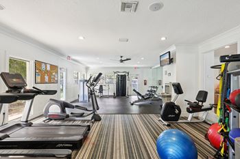 A gym with a treadmill, exercise balls and other equipment.